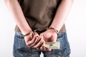 man in handcuffs holding money