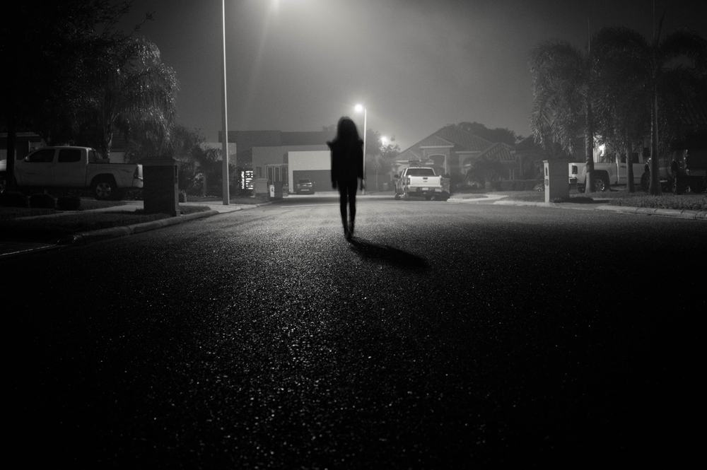 person walking down dark street alone