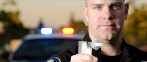 A police officer holding up a breathalyzer during a dui traffic stop