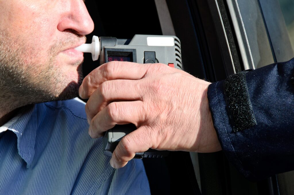 man taking a breathalyzer test at a traffic stop