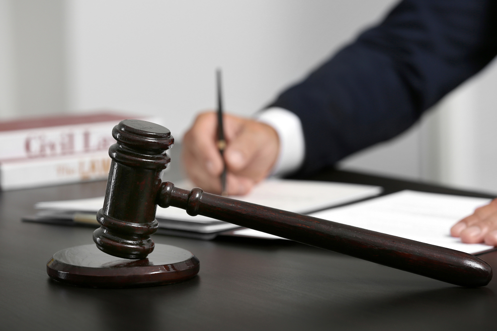 lawyer writing on legal pad with gavel in the foreground