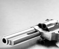 A close-up of a silver revolver resting on a metallic surface, emphasizing the concept of firearm rights and legal restrictions.