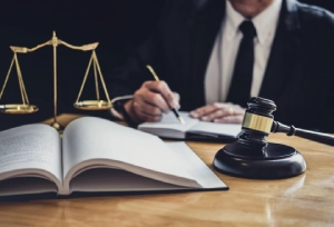 A lawyer in an office preparing for a criminal defense case taking notes from a law book on his desk.