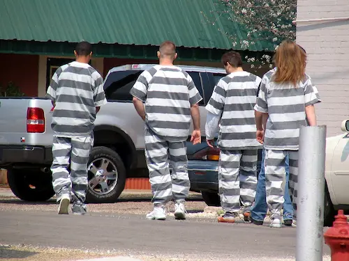 Four inmates in stripped grey and white jumpsuits
