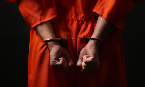 Handcuffed person in an orange jumpsuit, illustrating the issue of juvenile arrests in Florida.